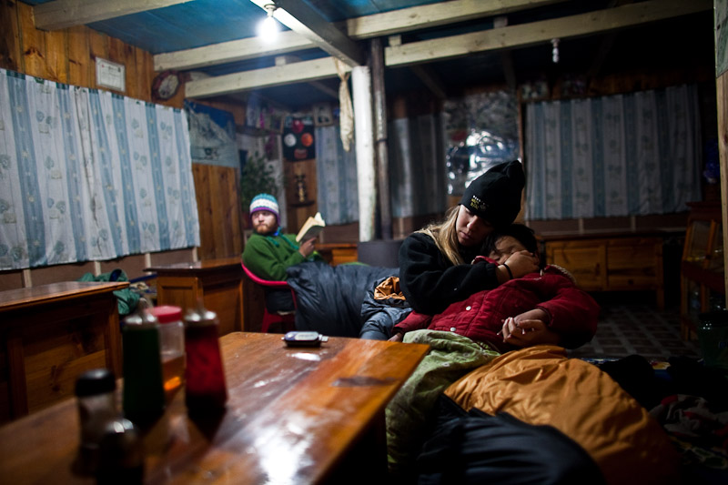 Lyndsay making a moment with a sherpa kid we hung out with for the evening; Graham enjoys some reading near the warm stove.